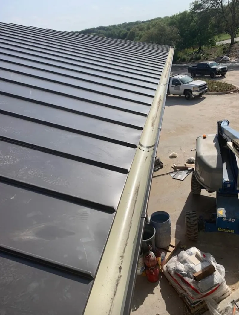 Standing seam panel and gutter detail on a metal roofing jobsite in Angleton